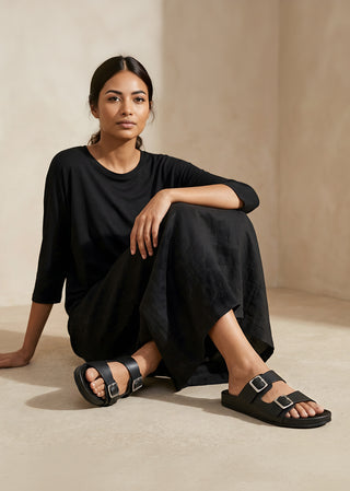 Copardo Deli black leather sandals worn by woman in minimalist indoor setting