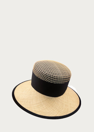Handcrafted natural fiber sun hat with open-weave crown and black band detail on a neutral background.