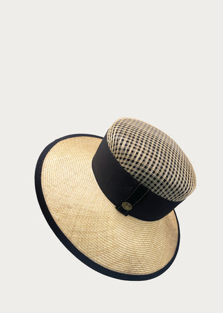 Wide-brim natural fiber hat with structured open-weave crown and black trim viewed from above.