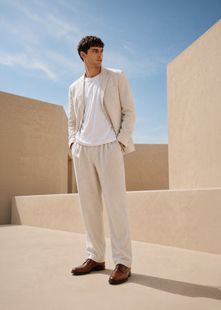 Man wearing brown leather lace-up shoes styled with relaxed tailoring in a minimalist architectural setting.