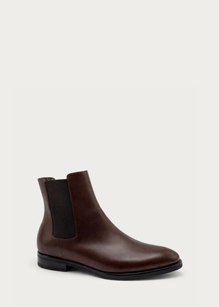 Single brown leather Chelsea boot with elastic side panels on a light neutral background.